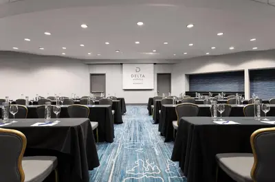 a conference room with tables and chairs and a screen at Delta Hotels by Marriott Woodbridge in Iselin