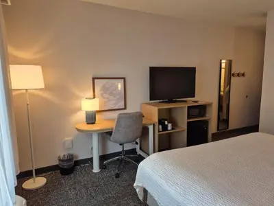 a hotel room with a desk with a television and a bed at Spark by Hilton Lancaster in Lancaster