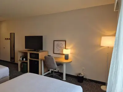 a hotel room with a desk with a television and a bed at Spark by Hilton Lancaster in Lancaster