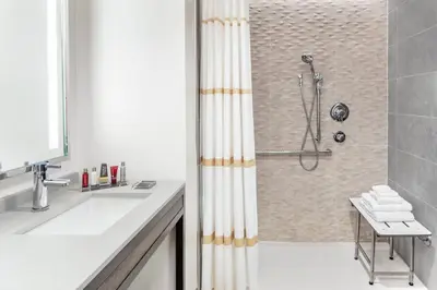 a white bathroom with a shower and a sink at Lancaster Marriott at Penn Square in Lancaster