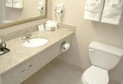 a bathroom with a toilet and a sink and a mirror at Ramada by Wyndham East Orange in East Orange