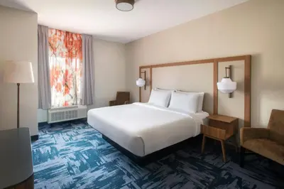 a hotel room with a large bed and a chair at Fairfield Inn & Suites by Marriott Somerset in Somerset