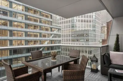 a balcony with a table and chairs and a large window at The Gotham Hotel in New York