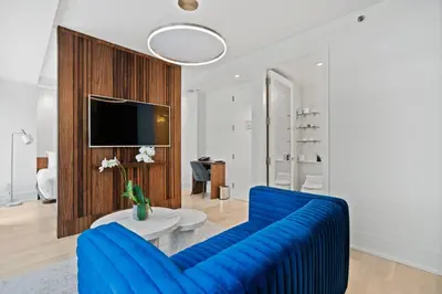 a living room with a blue couch and a tv at The Gotham Hotel in New York