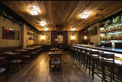 a restaurant with tables and chairs and a bar at The Gotham Hotel in New York