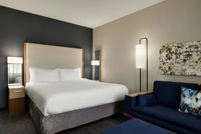 a bedroom with a large bed and a blue chair at Courtyard Wilmington Brandywine in Wilmington