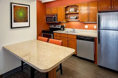 a kitchen with a table and a stainless steel refrigerator at Residence Inn Cherry Hill Philadelphia in Cherry Hill