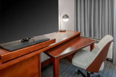 a desk with a television and a chair in a room at Courtyard Reading Wyomissing in Reading