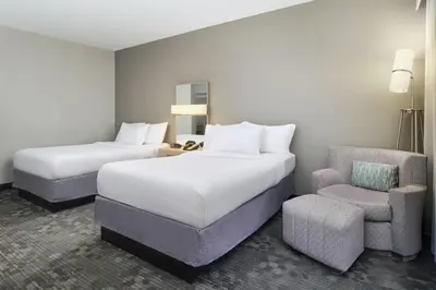 a hotel room with two beds and a chair at Courtyard by Marriott Scranton Montage Mountain in Moosic
