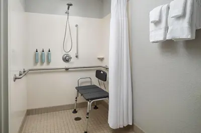 a shower with a chair in a bathroom at Courtyard by Marriott Scranton Montage Mountain in Moosic