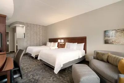a hotel room with two beds and a couch at Courtyard by Marriott Middletown Goshen in Middletown
