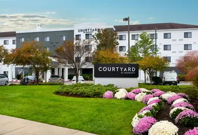 a sign for a courthouse yard with pink and white flowers at Courtyard by Marriott Middletown Goshen in Middletown
