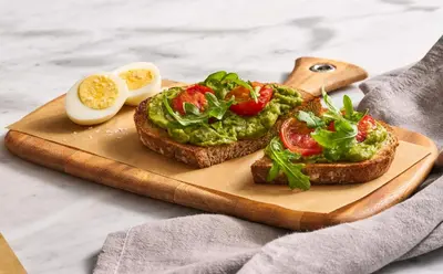 two slices of bread with avocado and eggs on a cutting board at Courtyard by Marriott Ewing Princeton in Ewing