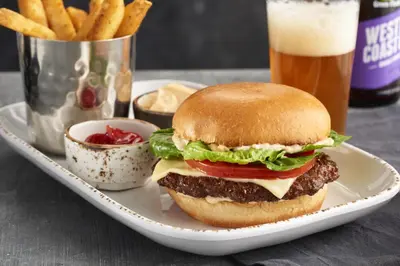 a hamburger on a plate with fries and a beer at Courtyard by Marriott Ewing Princeton in Ewing