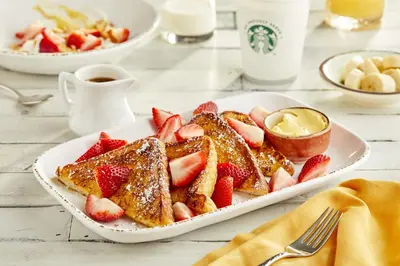 a plate of french toast with strawberries and a cup of coffee at Courtyard by Marriott Ewing Princeton in Ewing