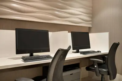 two computer monitors sitting on a desk with chairs at SpringHill Suites Ewing Township Princeton South in Ewing