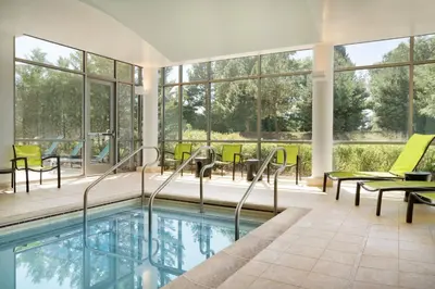 an indoor pool with chairs and tables and windows at SpringHill Suites Ewing Township Princeton South in Ewing
