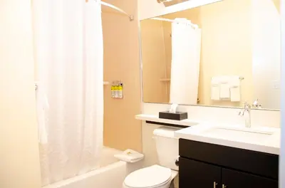 a bathroom with a toilet and a sink and a mirror at Candlewood Suites - Lancaster West by IHG in Lancaster