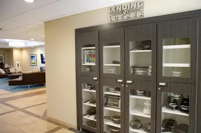 a row of lockers in a library with shoes in them at Candlewood Suites - Lancaster West by IHG in Lancaster