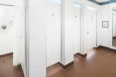 a row of stalls in a bathroom with white tiles at HI New York City Hostel in New York