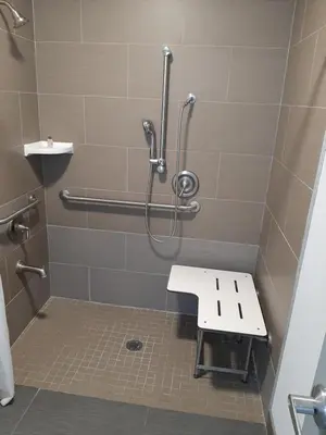 a bathroom with a shower with a bench in it at Hillside Motel Glen Mills in Glen Mills