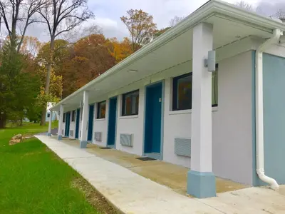 a building with blue and white columns and grass at Hillside Motel Glen Mills in Glen Mills