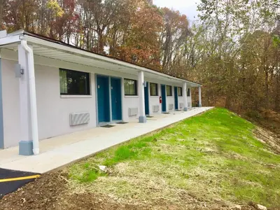 a building with blue doors and a grass field at Hillside Motel Glen Mills in Glen Mills