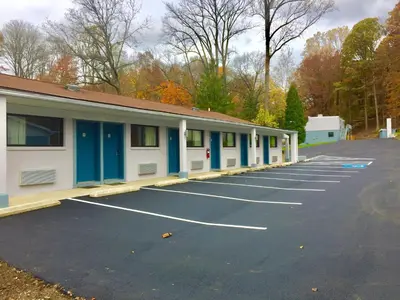 a parking lot with blue and white buildings at Hillside Motel Glen Mills in Glen Mills
