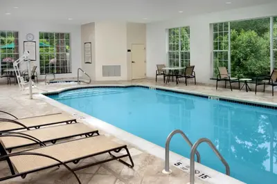 a pool with chairs and a table in a hotel at Staybridge Suites North Brunswick by IHG in North Brunswick