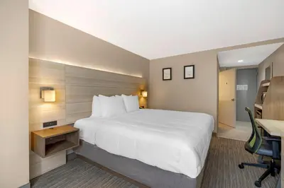a hotel room with a large white bed and a desk at Country Inn & Suites by Radisson, Staten Island in Staten Island