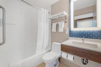 a bathroom with a toilet and a sink and a mirror at Country Inn & Suites by Radisson, Staten Island in Staten Island
