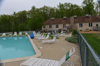 a swimming pool with lounge chairs and a playground at Appalachian Camping Resort Park Model 2 in Shartlesville