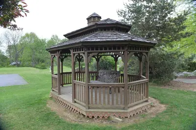 a wooden gazebo with two benches in the grass at Appalachian Camping Resort Park Model 2 in Shartlesville