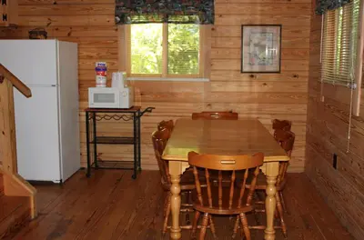 a kitchen with a table and chairs and a refrigerator at Appalachian Camping Resort Log Home 6 in Shartlesville