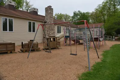 a playground in a yard next to a house at Appalachian Camping Resort Log Home 6 in Shartlesville