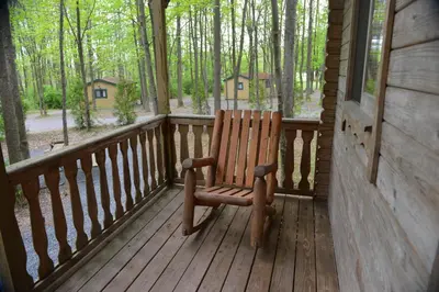 a wooden rocking chair sitting on the porch of a cabin at Appalachian Camping Resort Log Home 6 in Shartlesville