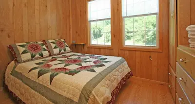 a bedroom with a bed and two windows at Robin Hill Camping Resort Premium Cottage 1 in Lenhartsville