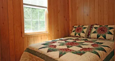 a bedroom with a quilt on a bed with a window at Robin Hill Camping Resort Premium Cottage 1 in Lenhartsville