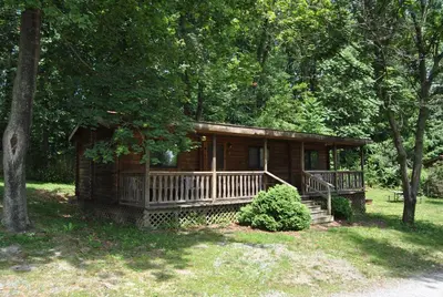 a log cabin in the woods with a porch at Robin Hill Camping Resort Two-Bedroom Cottage 6 in Lenhartsville