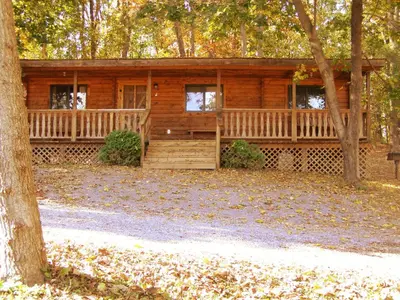 a log cabin in the woods with a tree at Robin Hill Camping Resort Two-Bedroom Cottage 6 in Lenhartsville