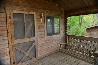 a wooden cabin with a door and a window at Robin Hill Camping Resort One-Bedroom Cottage 8 in Lenhartsville