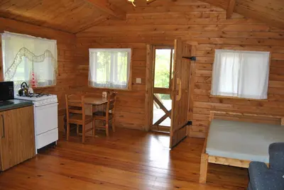a kitchen and dining room of a log cabin at Robin Hill Camping Resort One-Bedroom Cottage 8 in Lenhartsville
