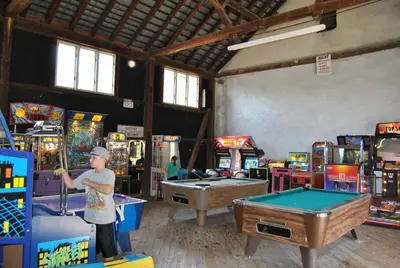 a man standing in a game room with pool tables at Robin Hill Camping Resort One-Bedroom Cottage 8 in Lenhartsville