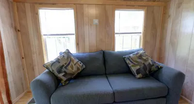 a blue couch in a room with two windows at Robin Hill Camping Resort Premium Cottage 9 in Lenhartsville