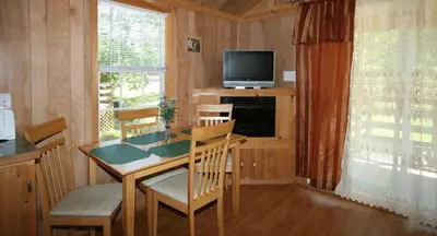 a dining room with a table and a television at Robin Hill Camping Resort Premium Cottage 9 in Lenhartsville