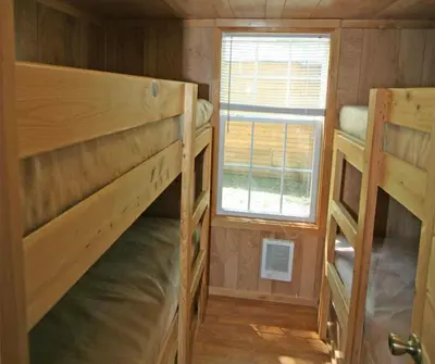 a small room with two bunk beds and a window at Robin Hill Camping Resort Premium Cottage 9 in Lenhartsville