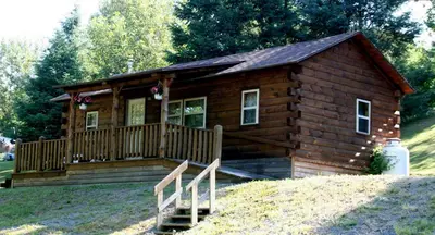 a small log cabin with a porch and a deck at Robin Hill Camping Resort Deluxe Cottage 13 in Lenhartsville