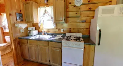a kitchen with a stove and a white refrigerator at Robin Hill Camping Resort Deluxe Cottage 13 in Lenhartsville