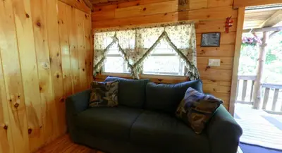a living room with a couch in a cabin at Robin Hill Camping Resort Deluxe Cottage 13 in Lenhartsville