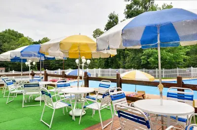 a group of tables and chairs with umbrellas next to a pool at Sun Valley Campground Cottage 4 in Maple Grove Park